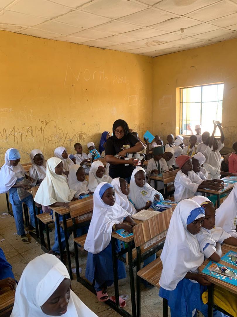 A volunteer sharing books with children at their desks